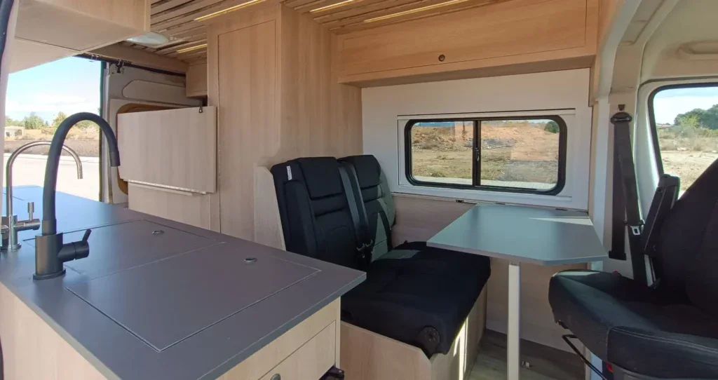 Amplio interior de furgoneta camper con cocina, asientos y espacio para descanso, completamente equipado para viajes de aventura y vida nómada.
