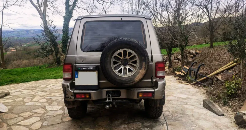 Furgoneta acondicionada para viajes y campamentos al aire libre con neumáticos grandes y accesorios de homologación.