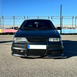 Coche negro en pista de pruebas con valla de seguridad, listo para inspección de homologación de vehículo.
